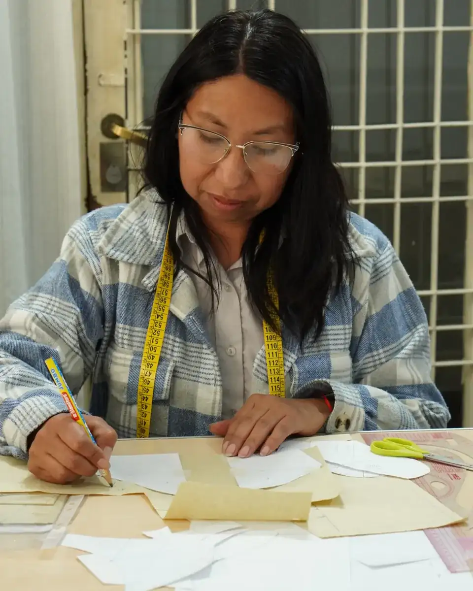 Alumna trazando moldes con cinta métrica en el taller de la escuela.