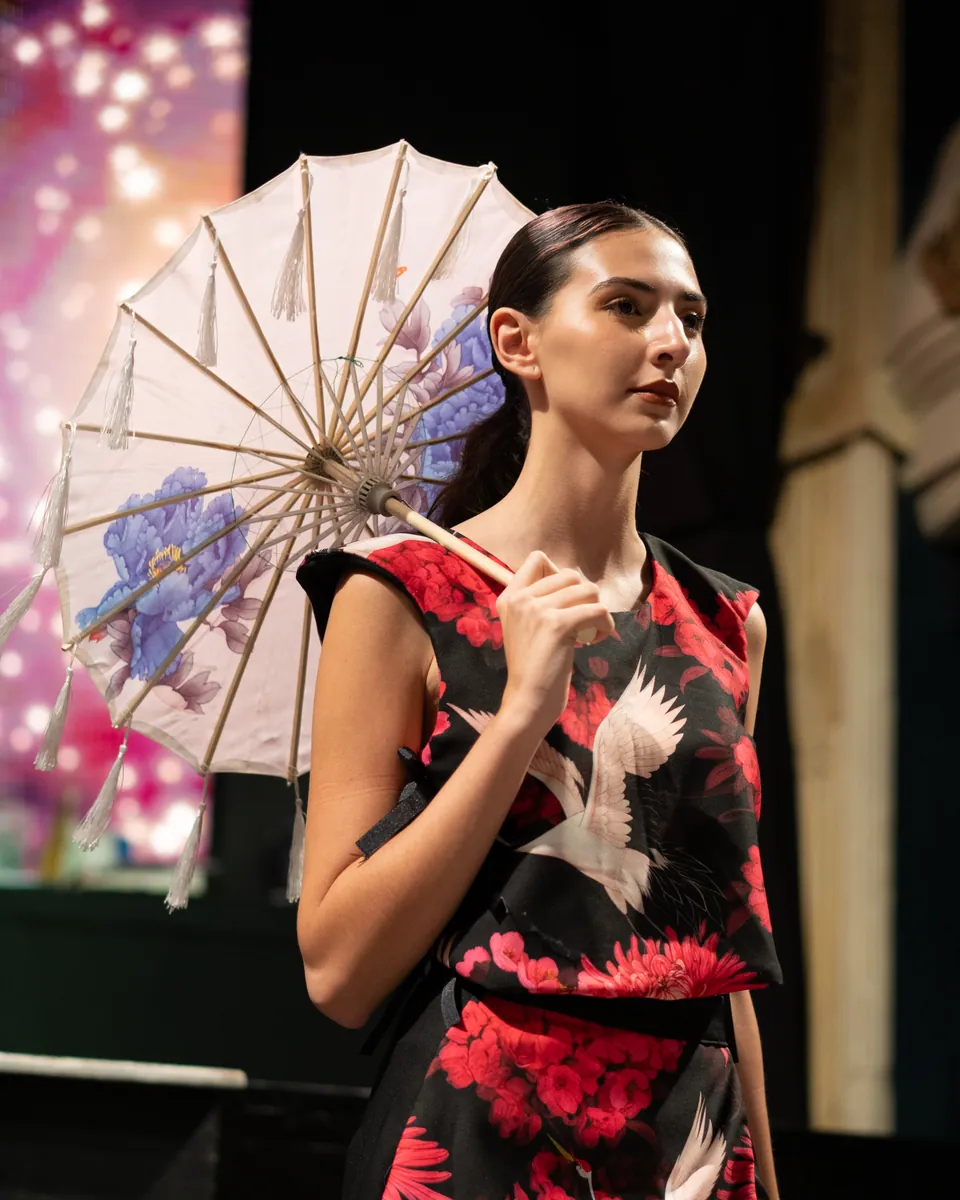 Desfile anual 2025: vestido con estampa floral y sombrilla en la pasarela.