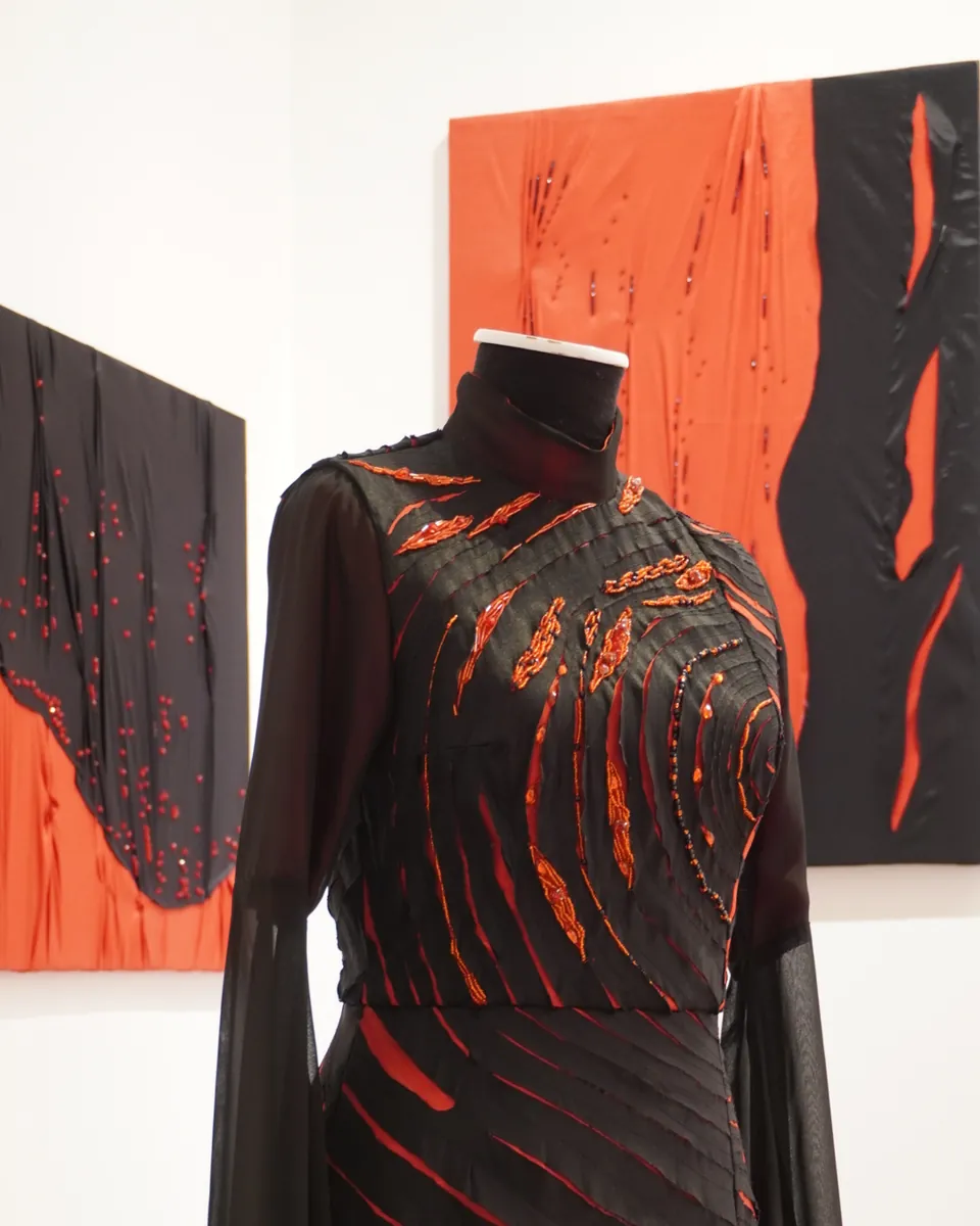 Vestido negro y naranja de una alumna de la Diplomatura en Diseño de Indumentaria Textil, en exhibición.